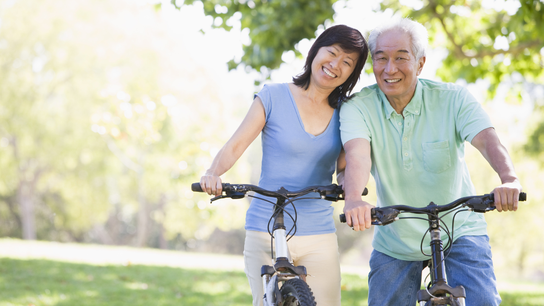 People riding bicycles along a scenic park path in Singapore, surrounded by greenery. Consider integrating health screening Singapore into your wellness routine.