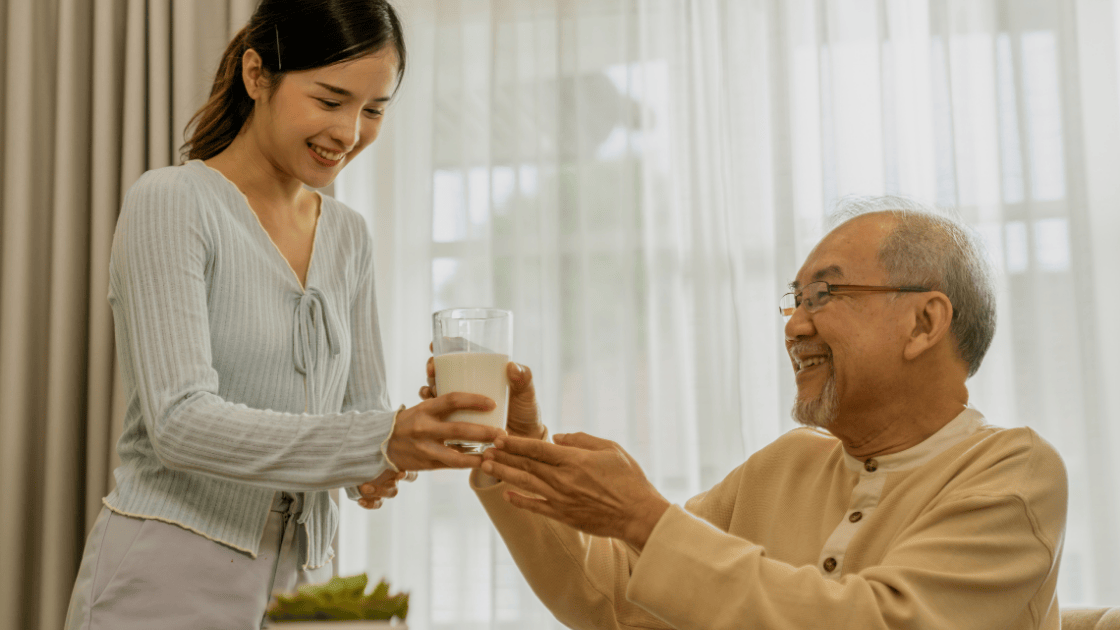 Older Asian man drinking milk to support bone health, emphasizing the importance of health screening SG for older adults