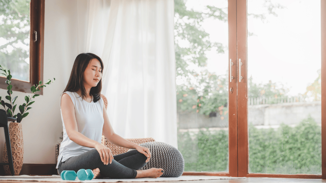 An Asian woman practicing meditation outdoors, promoting mindfulness and wellness after a health screening SG.