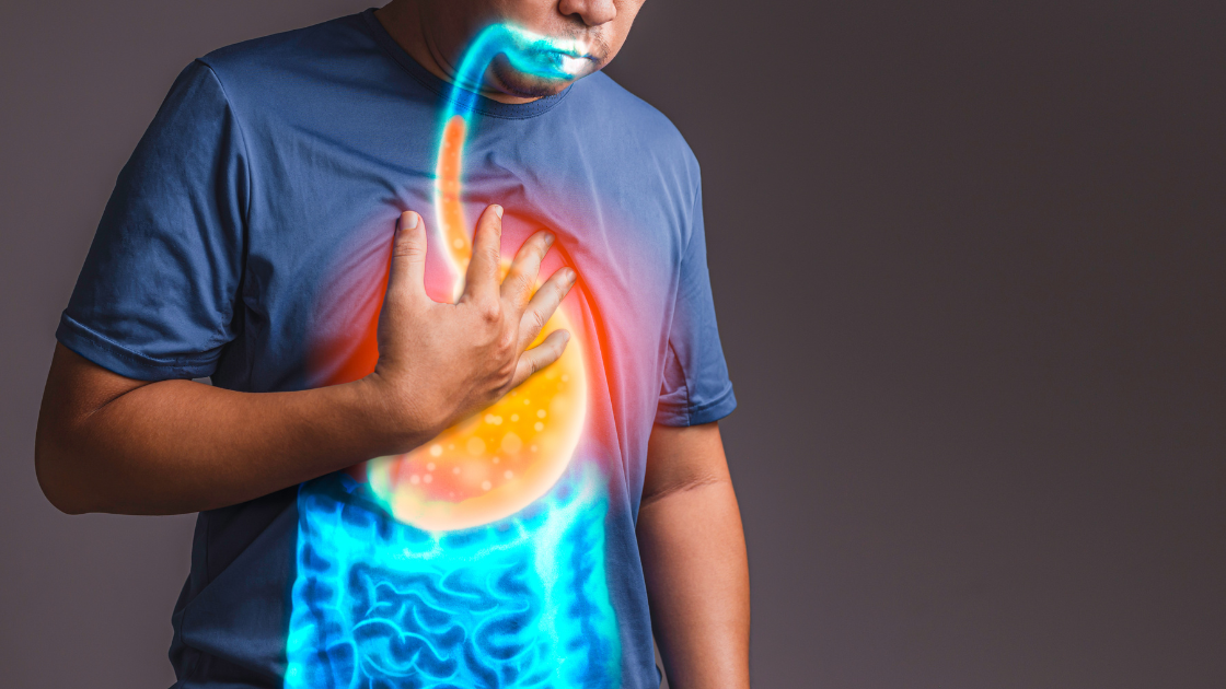 Asian man clutching his chest in discomfort from acid reflux or GERD symptoms