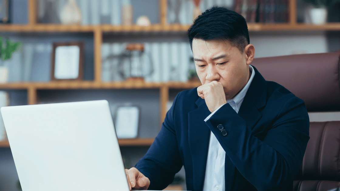 Asian man coughing persistently while working in air-conditioned Singapore office environment