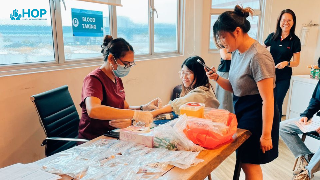 HOP healthcare professional drawing blood sample from Singapore office employee during onsite mobile health screening with professional medical equipment and sterile procedures