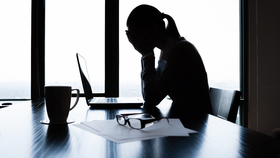 Stressed businesswoman experiencing workplace burnout at office desk in Singapore, showing need for health screening.