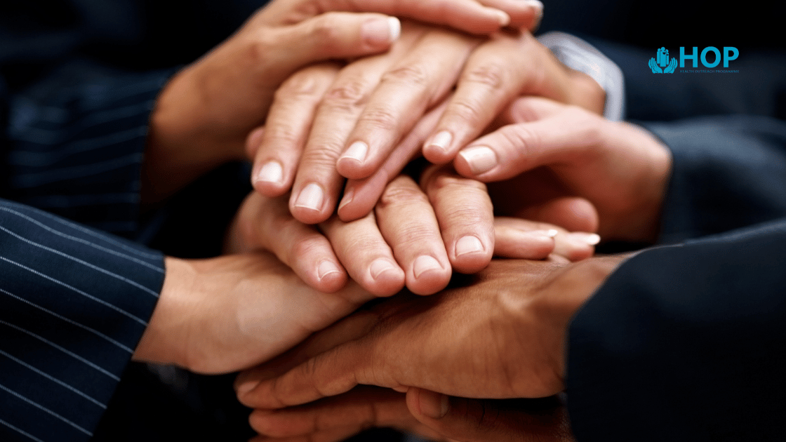 Corporate workers hands stacked together showing unity in workplace wellness health screening Singapore