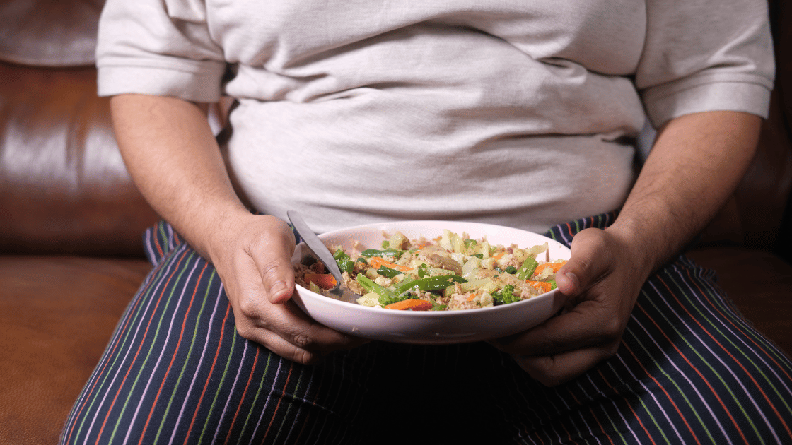 Man with obesity holding plate of vegetables for healthy diet as part of obesity management Singapore program