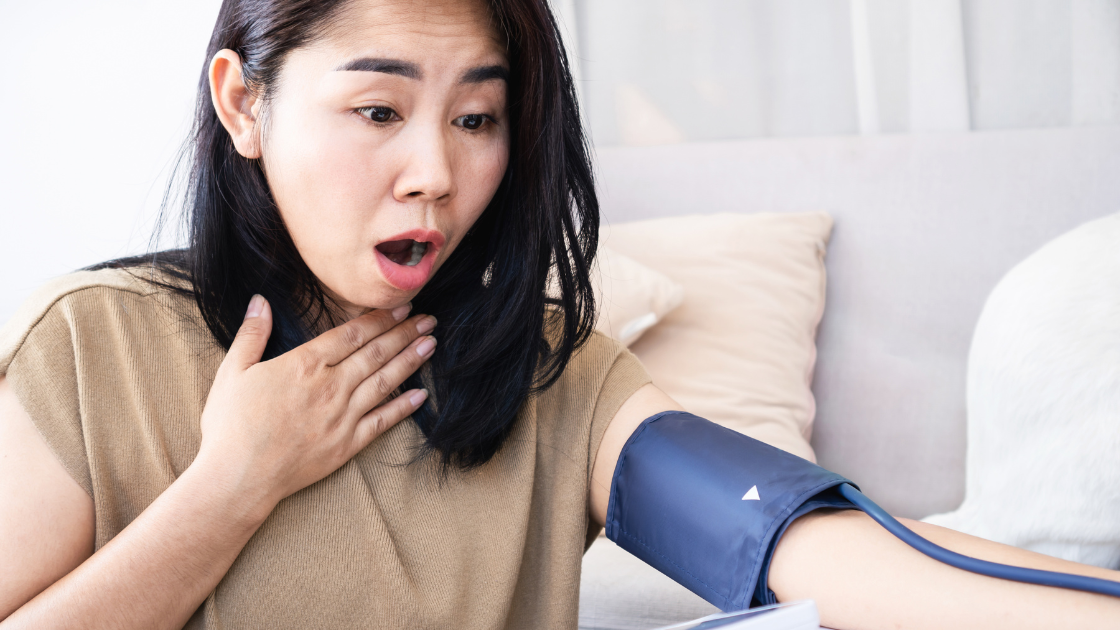 Concerned woman checking blood pressure at home with digital monitor showing elevated reading in Singapore
