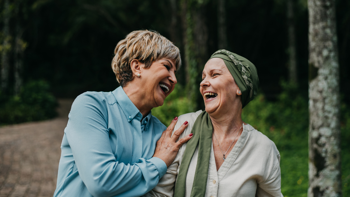 Cancer screening Singapore - two women cancer survivors smiling and talking together, showing positive outcomes with early detection and support