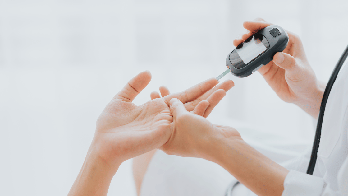 Healthcare professional performing blood glucose test on patient's finger for prediabetes Singapore screening at medical clinic