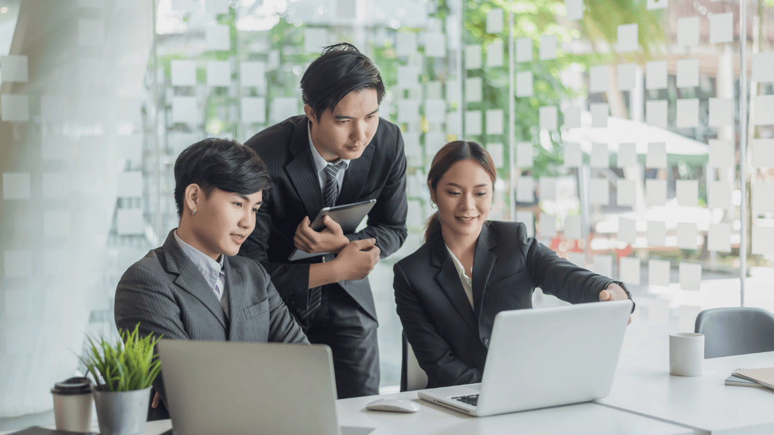 Team of employees collaborating at workplace discussing workplace wellness screenings on laptop screens