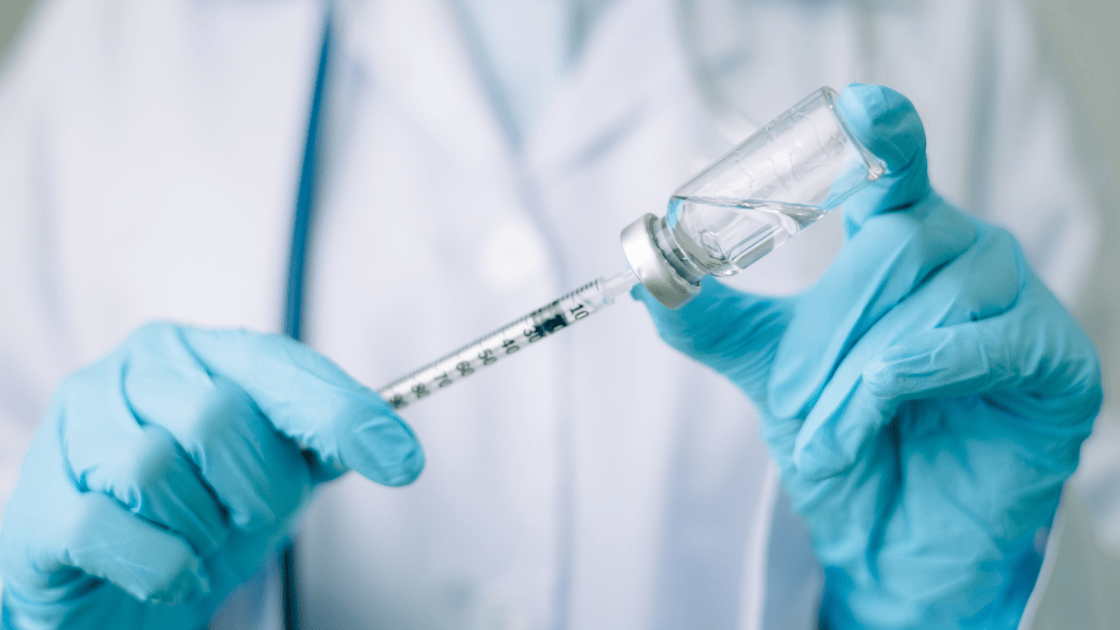 Healthcare nurse holding syringe and flu vaccine vial, preparing to administer flu vaccination to patient