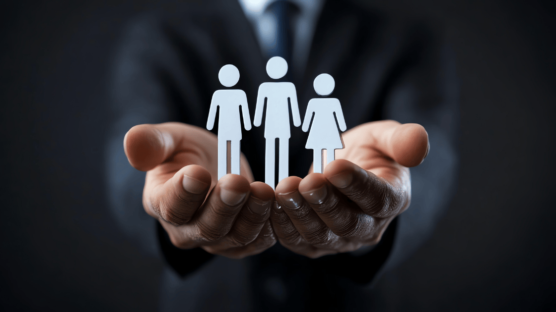 Paper art showing male and female workers standing on a man's palm, representing workplace wellness and employer care for employee wellbeing