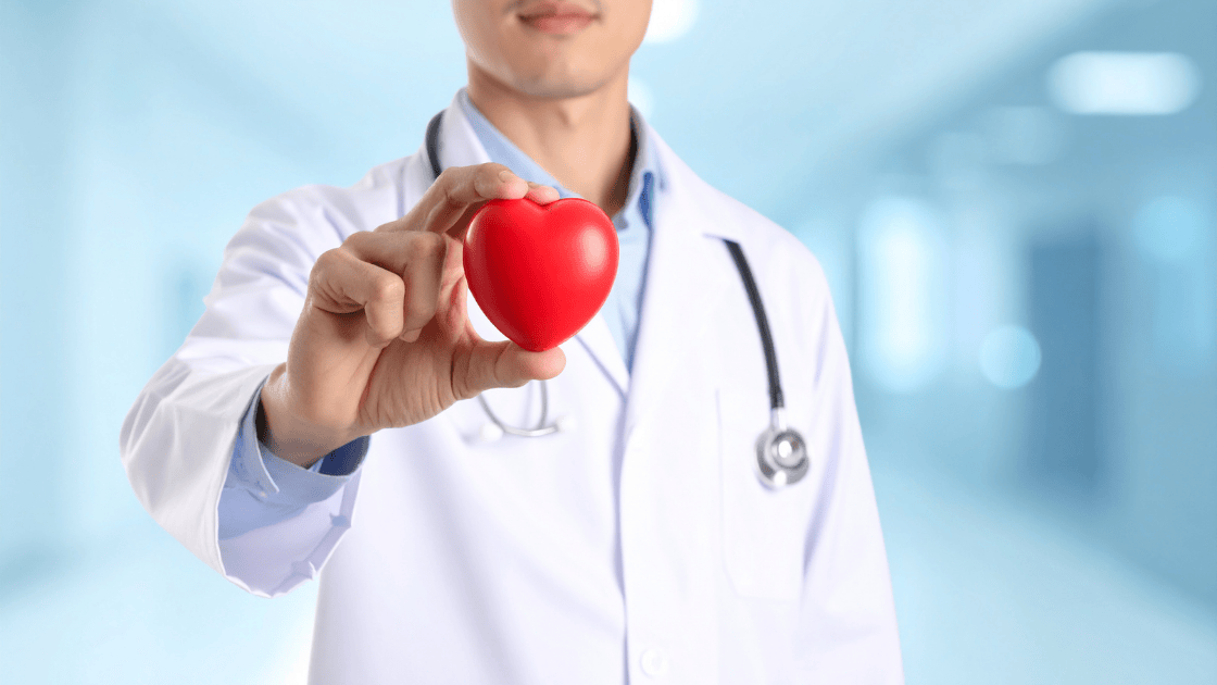Doctor hand holding red heart-shaped prop representing cardiac health screening Singapore