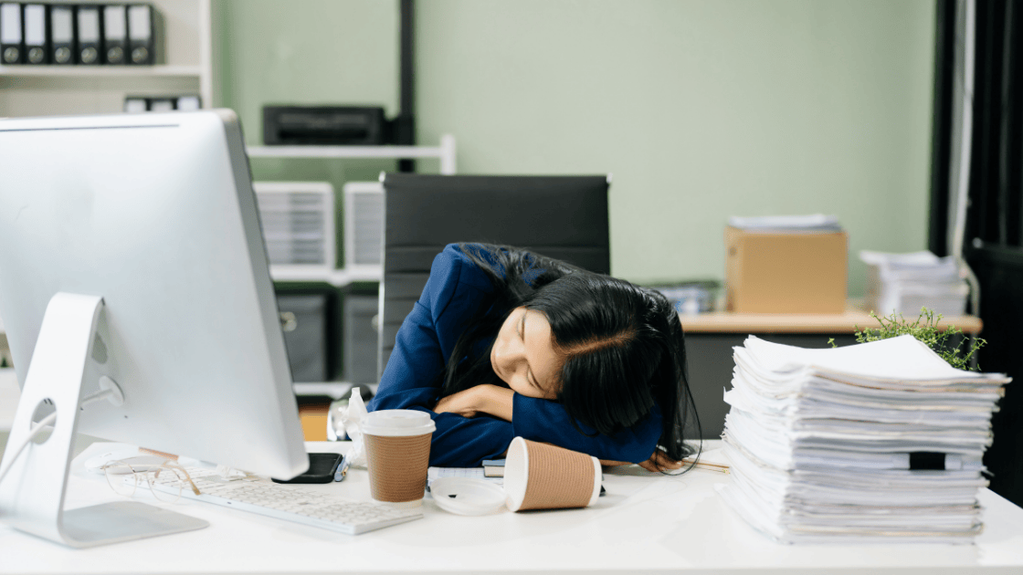 Exhausted young professional at desk requiring fatigue screening Singapore to identify iron deficiency vitamin D thyroid issues