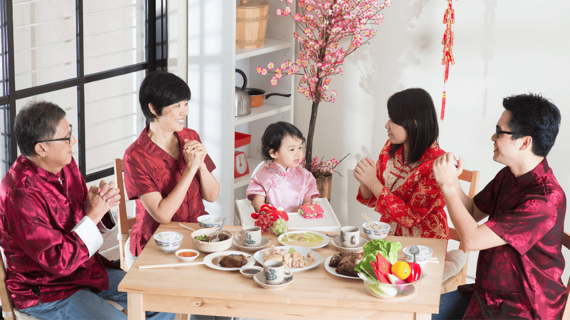 Multi-generation Chinese family gathered around reunion dinner table during Chinese New Year celebration discussing health and wellness