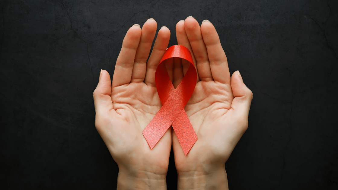 Hand holding a red ribbon — symbol of HIV awareness — representing HIV testing and prevention services at HOP Medical Centre Singapore