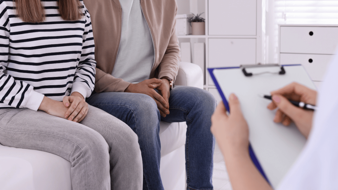 Couple sitting together during a consultation while a doctor takes notes, representing STD testing discussions at HOP Medical Centre